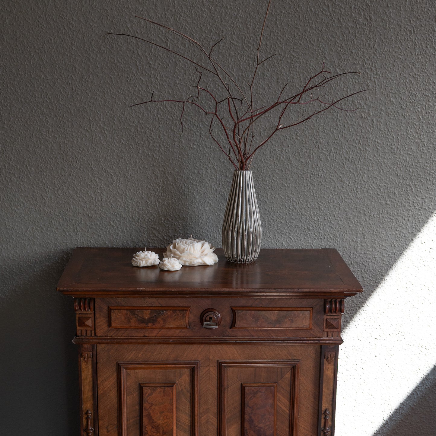 Kerzen-Set Bløma bestehend aus großer Pfingstrosenform plus zwei kleinere Blüten, natürlicher Cremeton, Designkerzen, Rapswachs, handgefertigt in Hamburg, 100 % pflanzlich & nachhaltig. Studio Z. Dekoriert auf barockem Tisch vor grauer Wand neben Vase und Lichtschattenspiel.