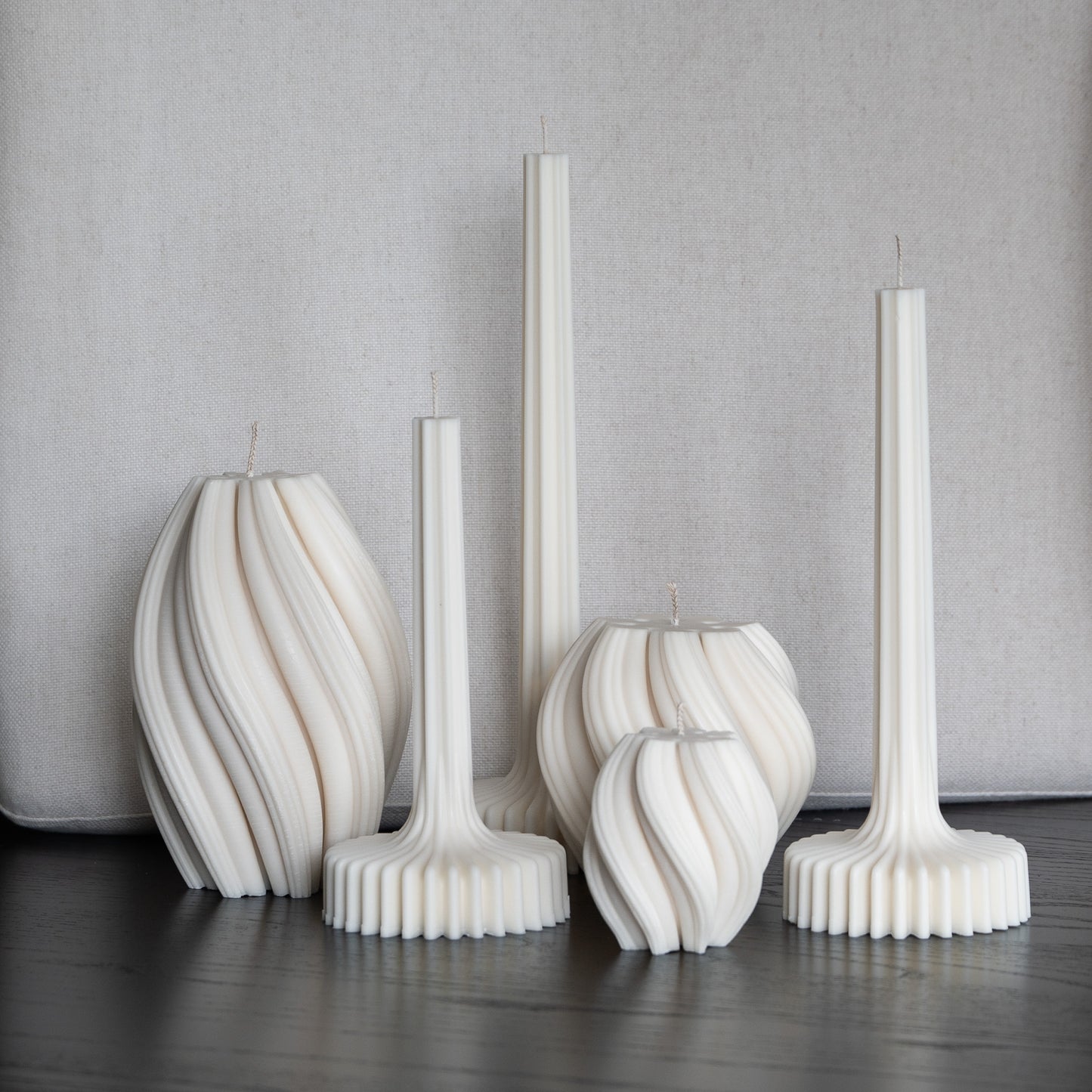Auswahl von Kerze Fylda und Bøluna, in natürlichem Cremeton – Rapswachs, handgefertigt in Hamburg, 100 % pflanzlich & nachhaltig. Studio Z. Geriffelte Struktur mit Plateaufuß und bauchige Wellenform, 6 Stück dekoriert auf schwarzem Tisch vor hellem Hintergrund.