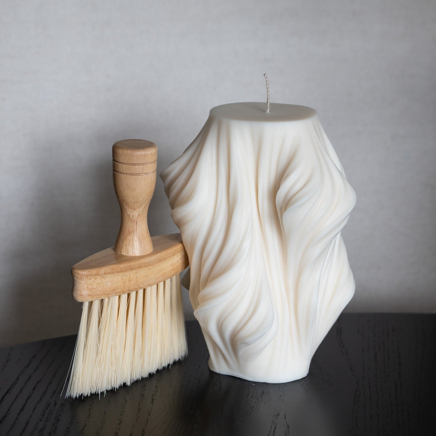 Slør Kerze L neben Pflegebürste mit Holzgriff zum Entfernen von Ruß und Staub.