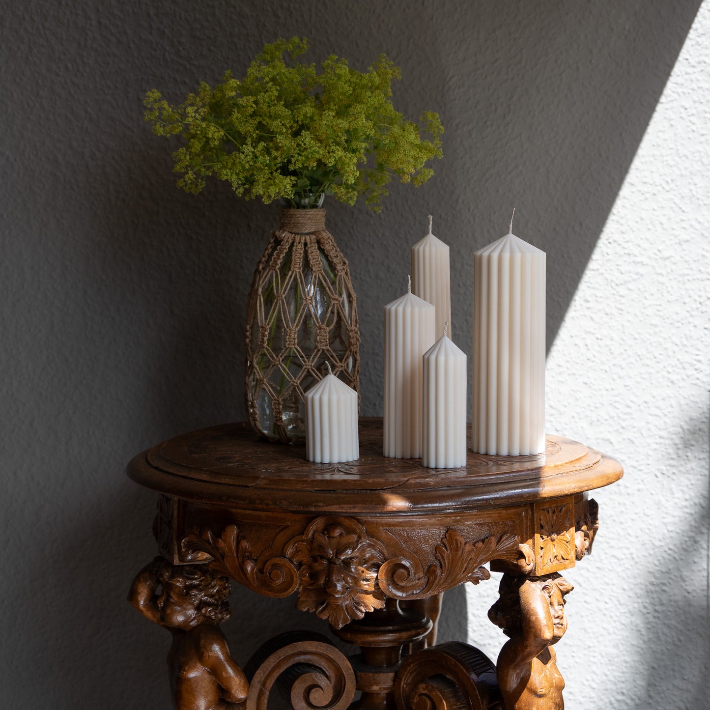 Kerzen Set Blocka in natürlichem Cremeton – skulpturale Designkerzen, Rapswachs, handgefertigt in Hamburg, 100 % pflanzlich & nachhaltig. Studio Z. Stumpenkerzen in Riffelstruktur. Dekoriert auf barockem Tisch im Schatten-Lichtspiel der Sonne mit Vase und Frauenmantelkraut.