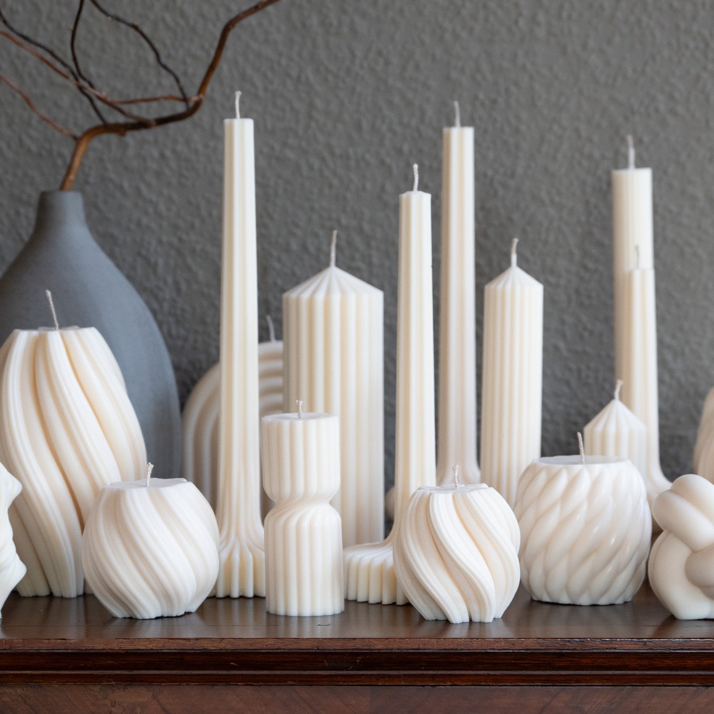 Kerzen verschiedene Formen und Größen in natürlichem Cremeton – skulpturale Designkerzen, Rapswachs, handgefertigt in Hamburg, skandinavisches Design, 100 % pflanzlich & nachhaltig. Studio Z. Stumpenkerzen in Riffelstruktur. Dekoriert auf barocker Kommode neben Vase.