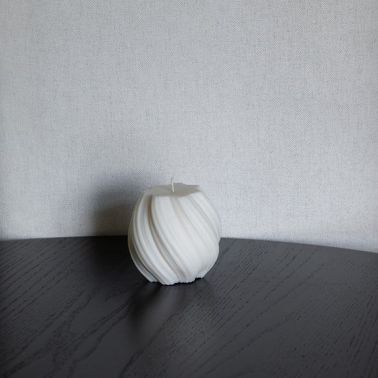 Kerze Bølge, bauchige, gewellte Stumpenkerze in natürlichem Cremeton – skulpturale Designkerzen aus Rapswachs, handgefertigt in Hamburg, 100 % pflanzlich & nachhaltig. Studio Z. Dekoriert auf schwarzem Tisch vor hellem Hintergrund.