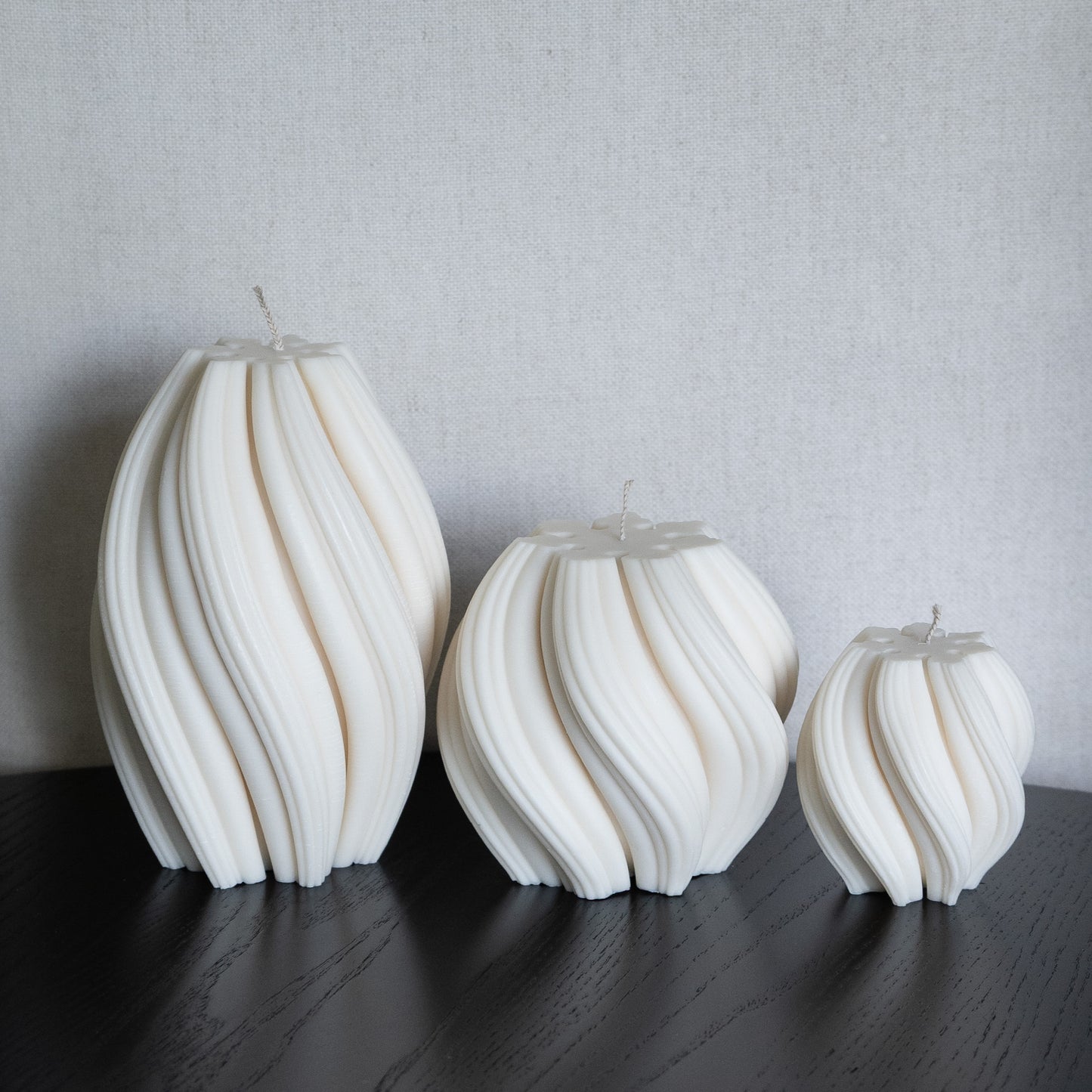 3er Kerzen Set Bøluna in natürlichem Cremeton – skulpturale Designkerzen, Rapswachs, handgefertigt in Hamburg, 100 % pflanzlich & nachhaltig. Studio Z. Stumpenkerzen in Wellenform, geschwungen und bauchig. Dekoriert auf schwarzem Tisch.