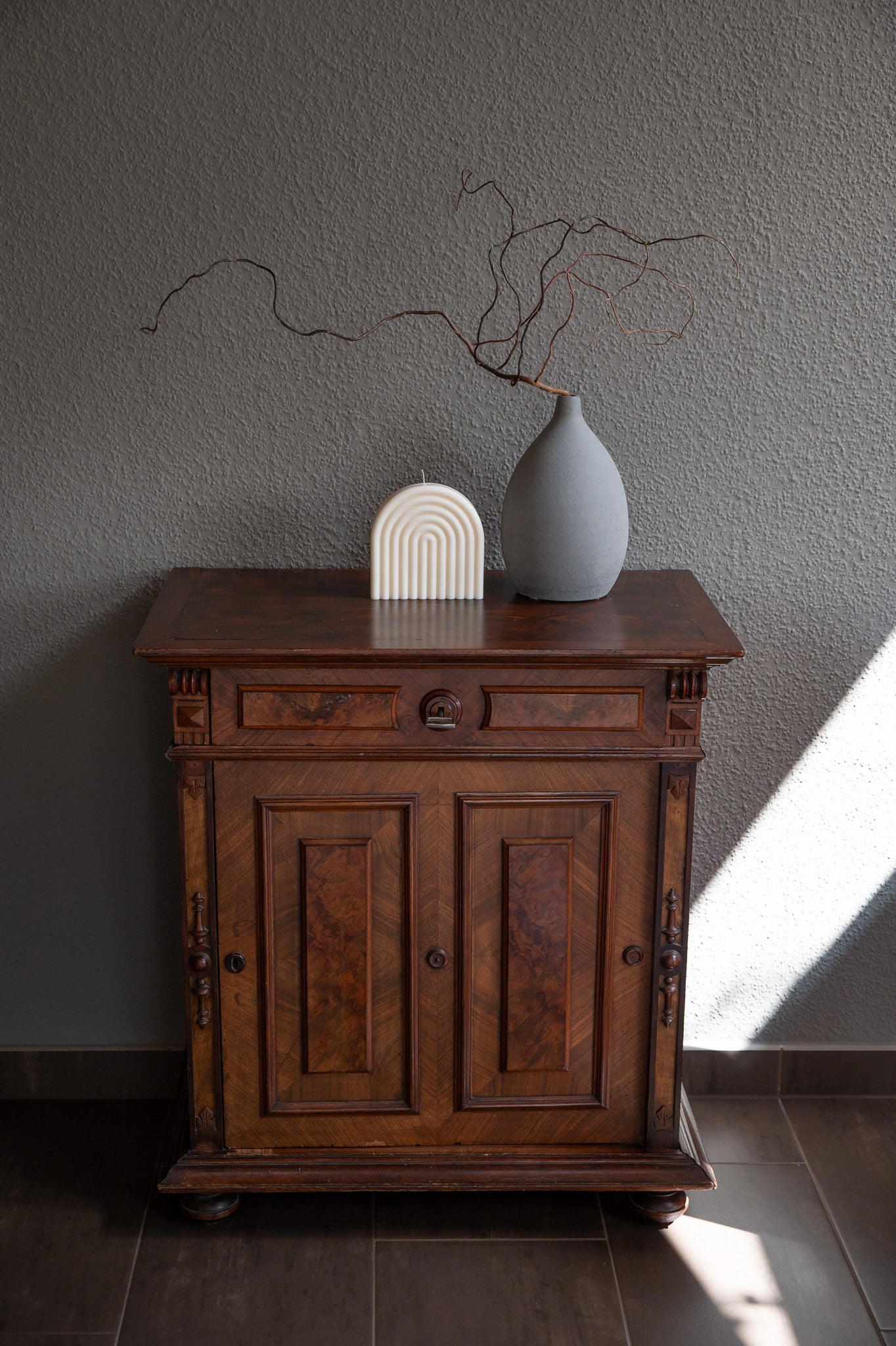 Kerze Farverig in natürlichem Cremeton – skulpturale Regenbogen Designkerzen, Rapswachs, handgefertigt in Hamburg, 100 % pflanzlich & nachhaltig. Studio Z. Dekoriert auf barockem Tisch im Schatten-Lichtspiel der Sonne mit Vase.