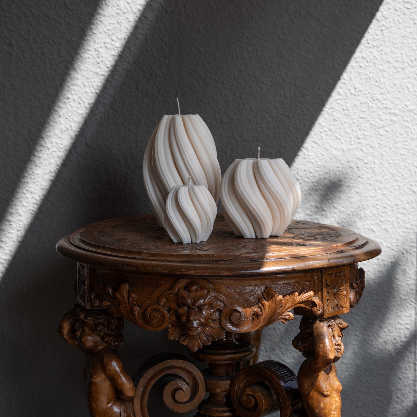 3er Kerzen Set Bøluna in natürlichem Cremeton – skulpturale Designkerzen, Rapswachs, handgefertigt in Hamburg, 100 % pflanzlich & nachhaltig. Studio Z. Stumpenkerzen in Wellenform, geschwungen und bauchig. Dekoriert auf barockem Tisch m Schattenspiel der Sonne.