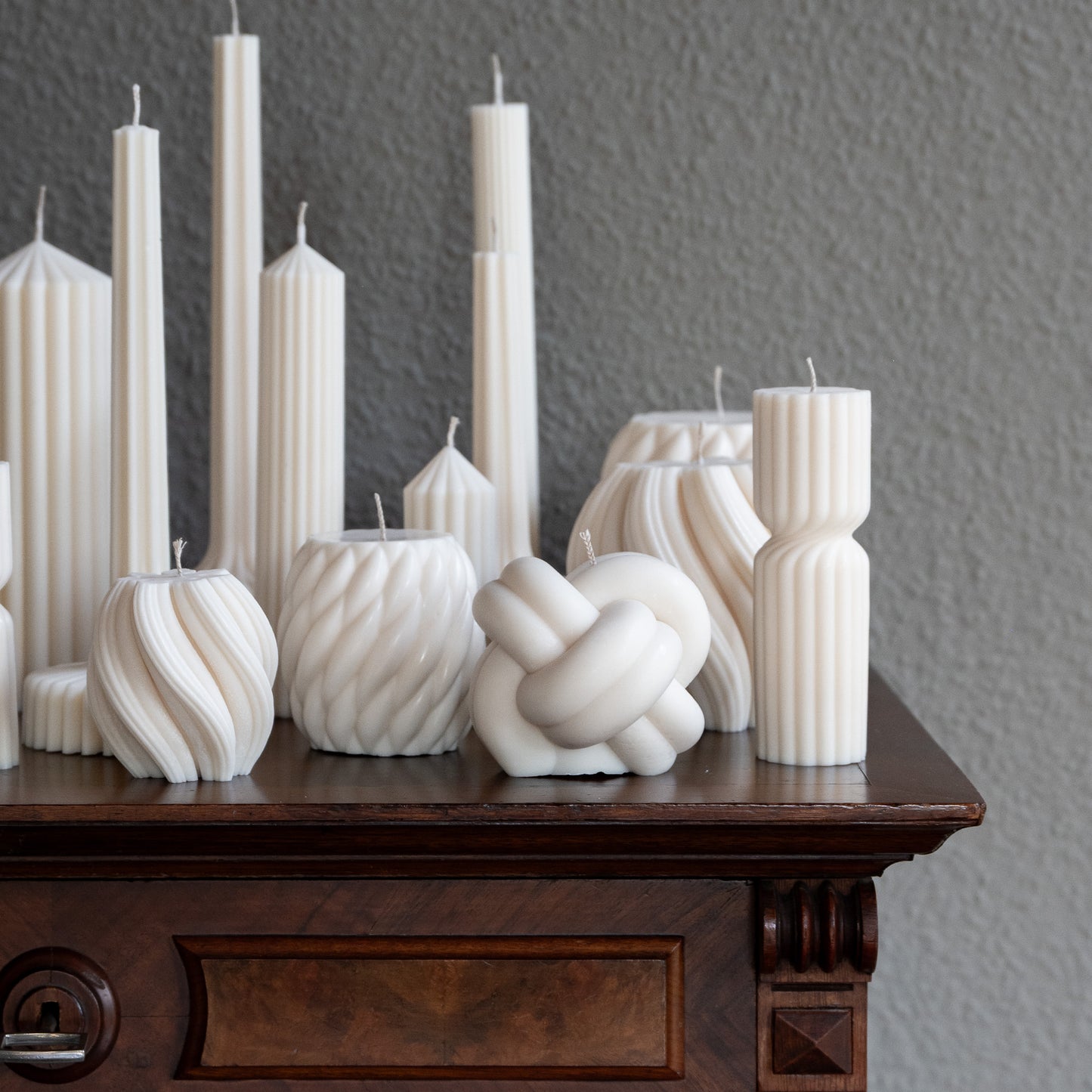 Verschiedene Kerzen Studio Z in natürlichem Cremeton – skulpturale Designkerzen und Stumpenkerzen, Rapswachs, handgefertigt in Hamburg, 100 % pflanzlich & nachhaltig. Dekoriert auf barocker Kommode mit Vase. Bøluna Slør farverig knøt knøv blocka bølge lys