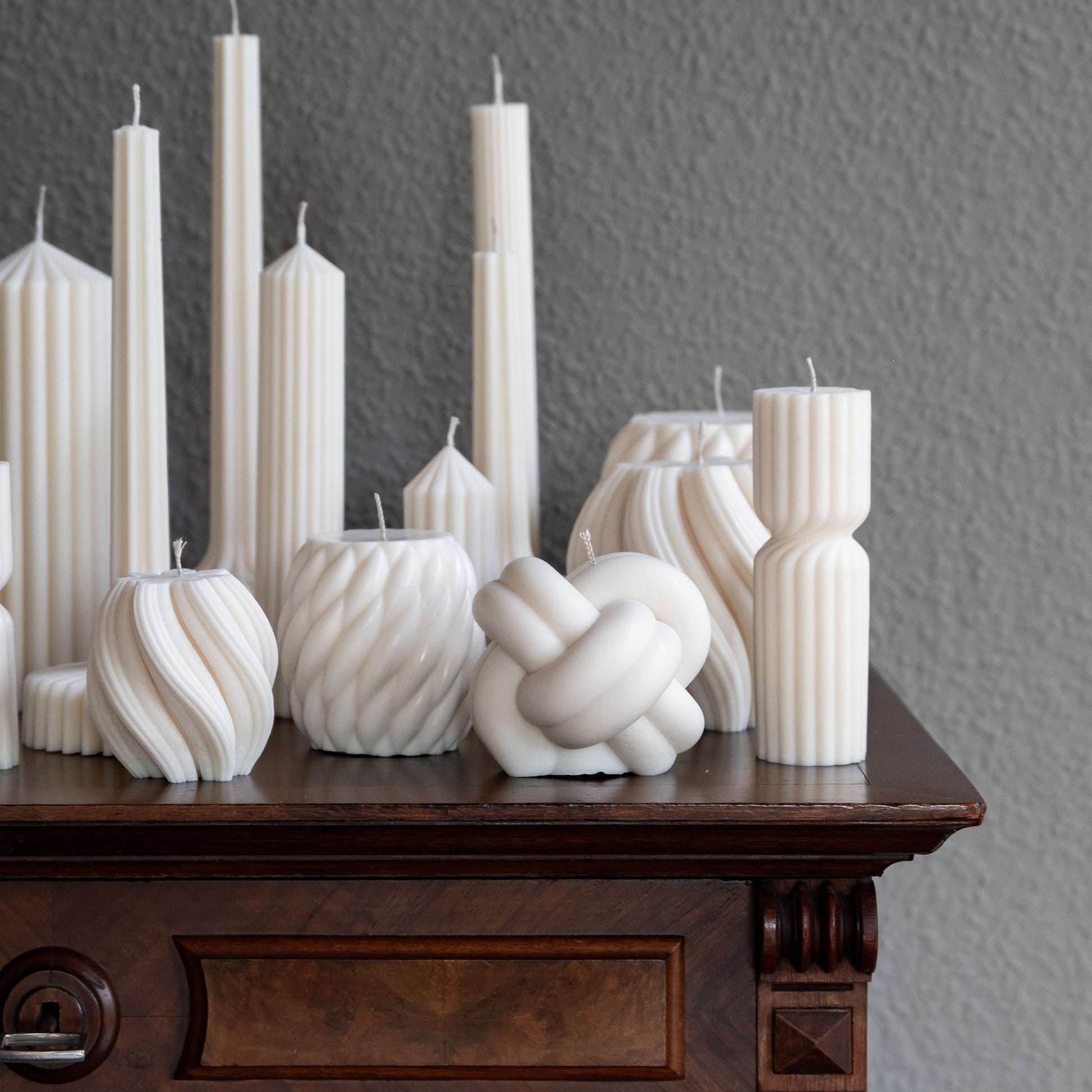 Verschiedene Kerzen Studio Z in natürlichem Cremeton – skulpturale Designkerzen und Stumpenkerzen, Rapswachs, handgefertigt in Hamburg, 100 % pflanzlich & nachhaltig. Dekoriert auf barocker Kommode mit Vase. Bøluna Slør farverig knøt knøv blocka bølge lys
