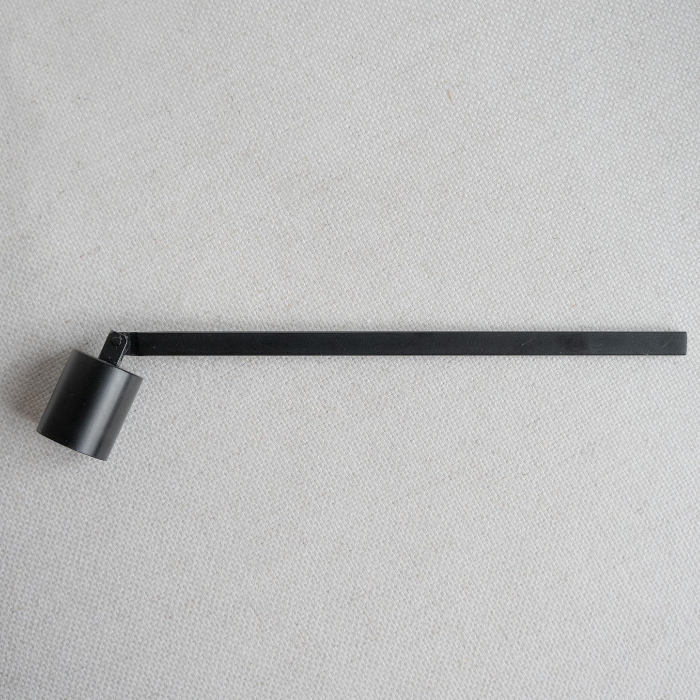 Schwarzer Kerzenlöscher aus Metall – Accessoire für Kerzenliebhaber:innen auf hellem Untergrund