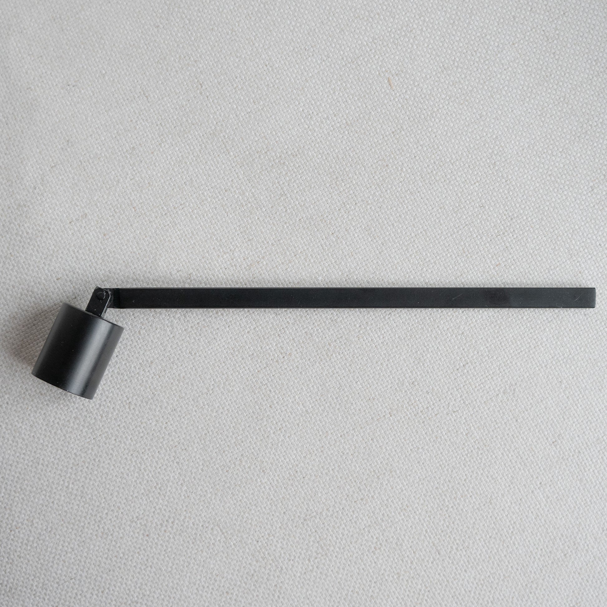 Schwarzer Kerzenlöscher aus Metall – Accessoire für Kerzenliebhaber:innen auf hellem Untergrund