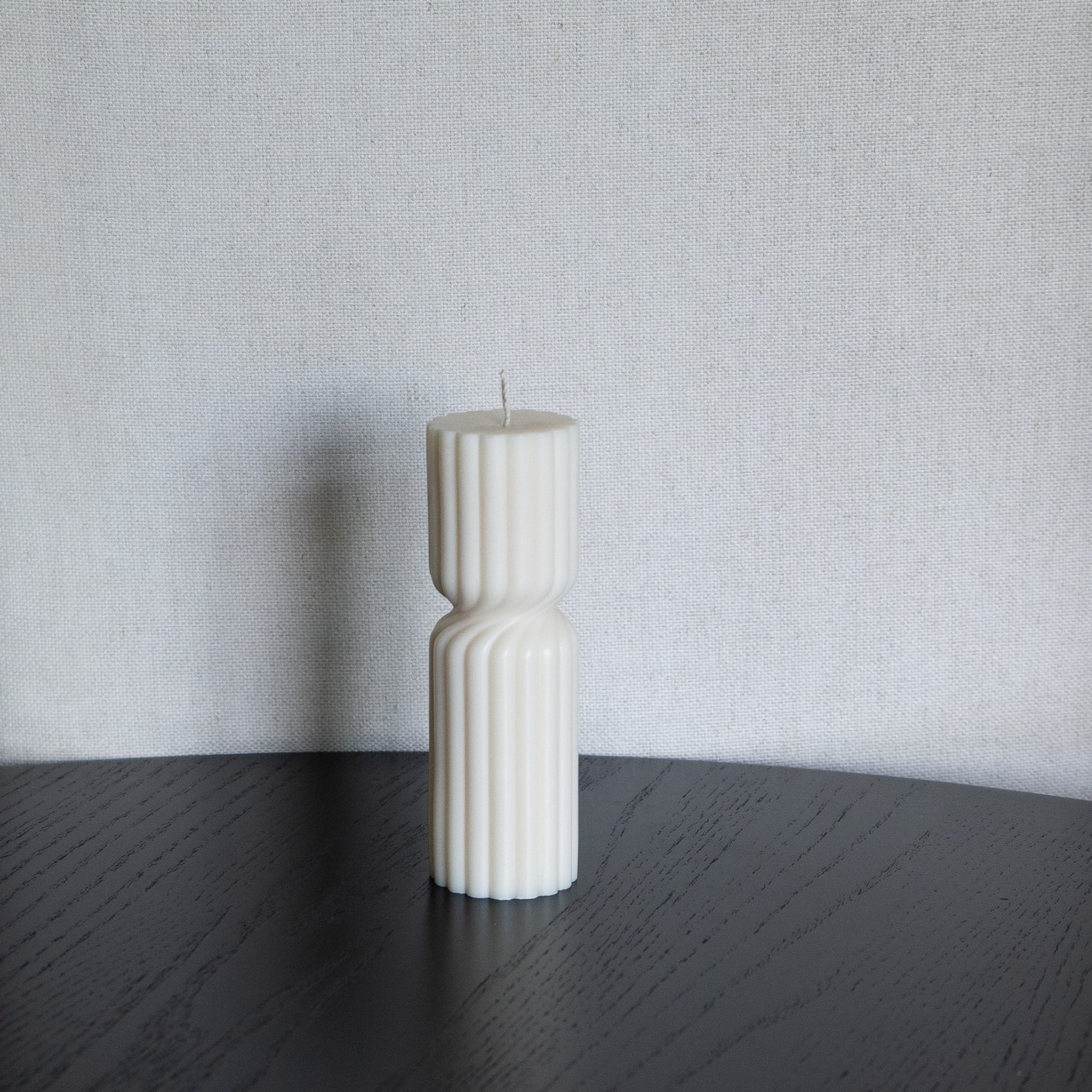 Kerze Støme gedrehte Stumpenkerze in natürlichem Cremeton – skulpturale längliche Designkerzen, Rapswachs, handgefertigt in Hamburg, 100 % pflanzlich & nachhaltig. Studio Z. Geriffelte Struktur., mittig gedreht Dekoriert auf schwarzem Tisch vor hellem Hintergrund.