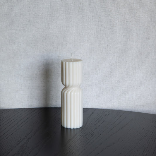 Kerze Støme gedrehte Stumpenkerze in natürlichem Cremeton – skulpturale längliche Designkerzen, Rapswachs, handgefertigt in Hamburg, 100 % pflanzlich & nachhaltig. Studio Z. Geriffelte Struktur., mittig gedreht Dekoriert auf schwarzem Tisch vor hellem Hintergrund.