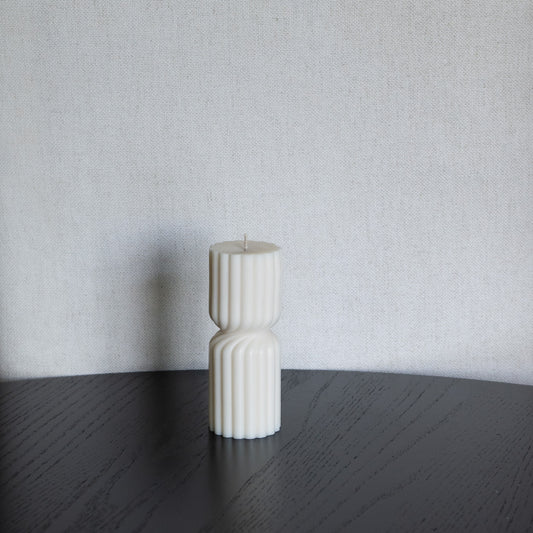 Kleine Kerze Støme gedrehte Stumpenkerze in natürlichem Naturfarbton – skulpturale längliche Designkerzen, Rapswachs, handgefertigt in Hamburg, 100 % pflanzlich & nachhaltig. Studio Z. Geriffelte Struktur., mittig gedreht Dekoriert auf schwarzem Tisch vor hellem Hintergrund.