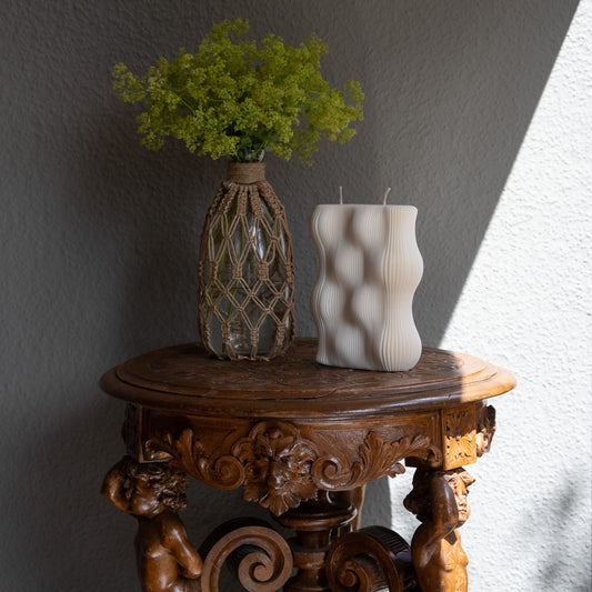 Væg Kerze in natürlichem Cremeton – Designkerzen aus Rapswachs, handgefertigt in Hamburg. 100 % pflanzlich & nachhaltig. Studio Z. Skulpturale Wellenform wie eine horizontale Wachswand. Dekoriert auf barockem Tisch im Schatten-Lichtspiel der Sonne mit Vase und Frauenmantelkraut.