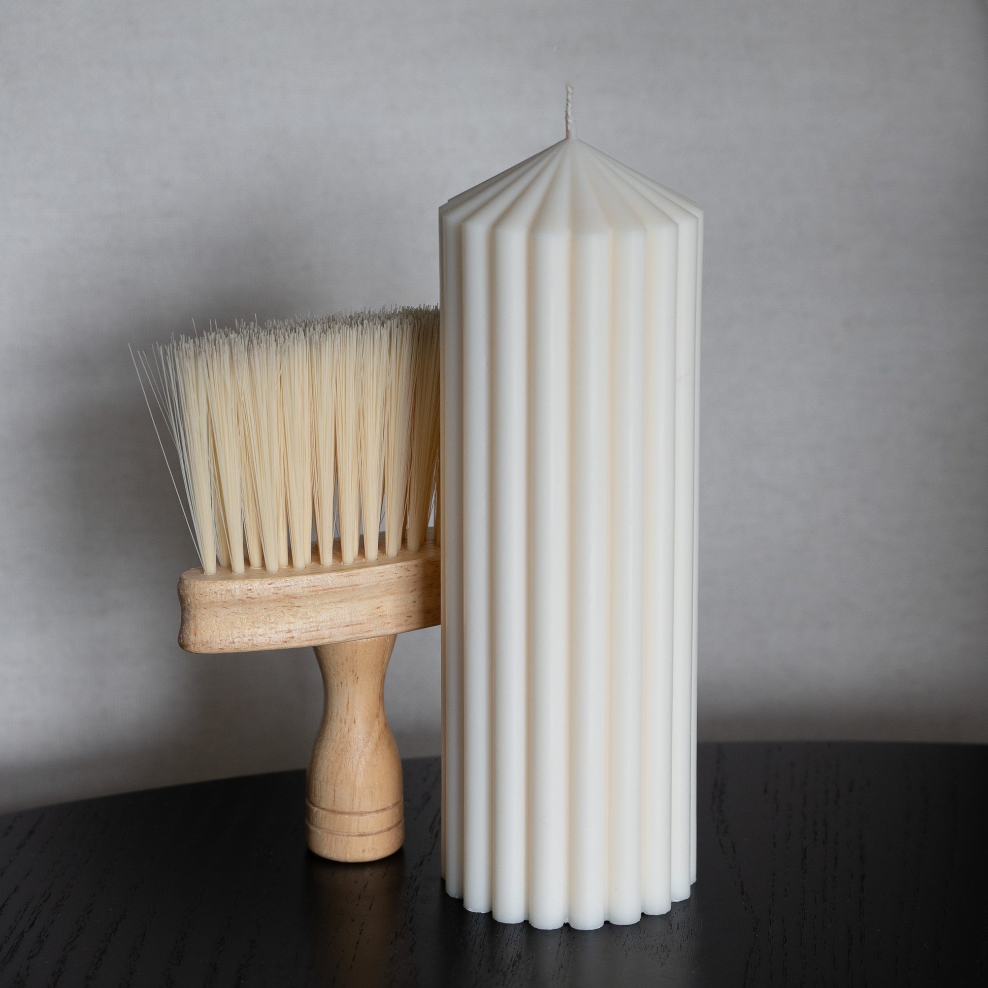 Blocka Kerze L neben Pflegebürste mit Holzgriff zum Entfernen von Ruß und Staub.